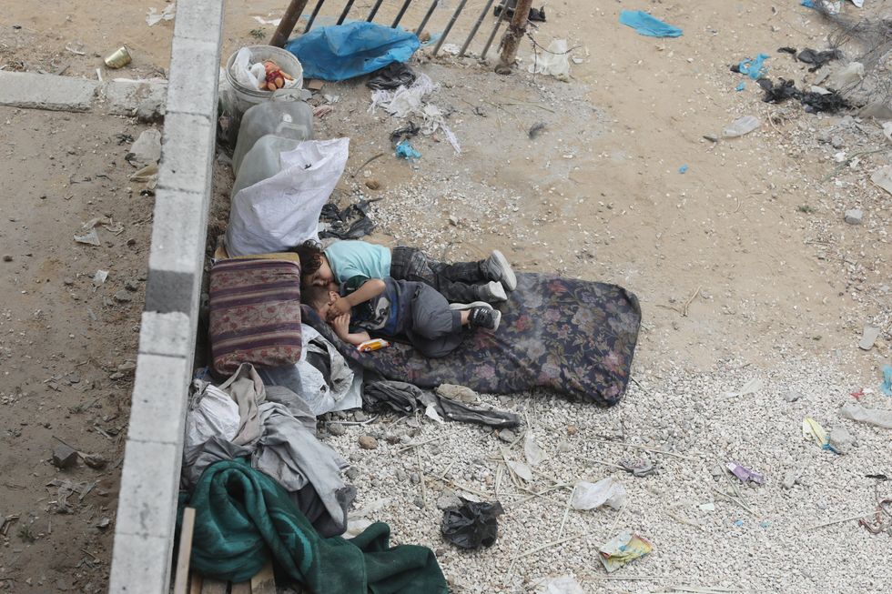 Two children sleep on a bed on the ground. Palestinians search for casualties at the site of an Israeli strike on a house, amid the ongoing Israel war on Gaza