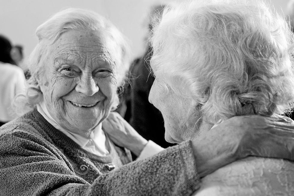 Two elderly women smiling at each other.