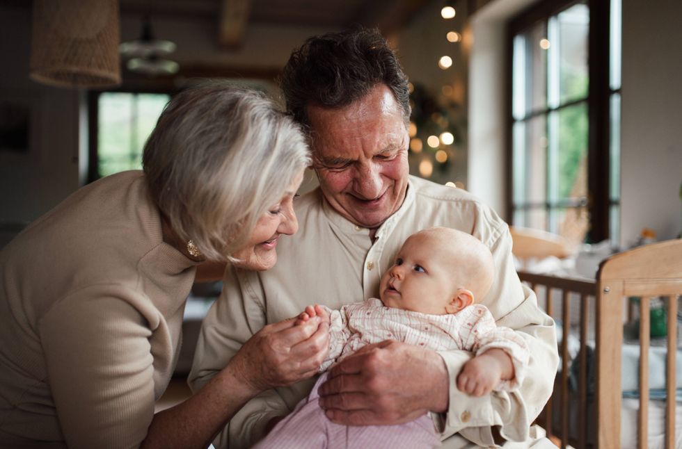 Two grandparents play with a grandchild sitting in the grandfather's lap