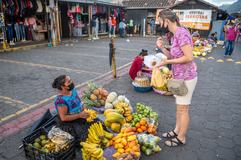 Two masked women at a fruit market in Antigua, Guatemala.