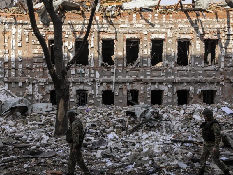 Two members of the Ukrainian military walk on the debris caused by Russian shelling in Kharkiv