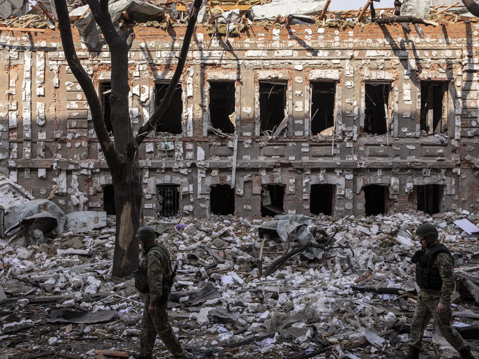 Two members of the Ukrainian military walk on the debris caused by Russian shelling in Kharkiv