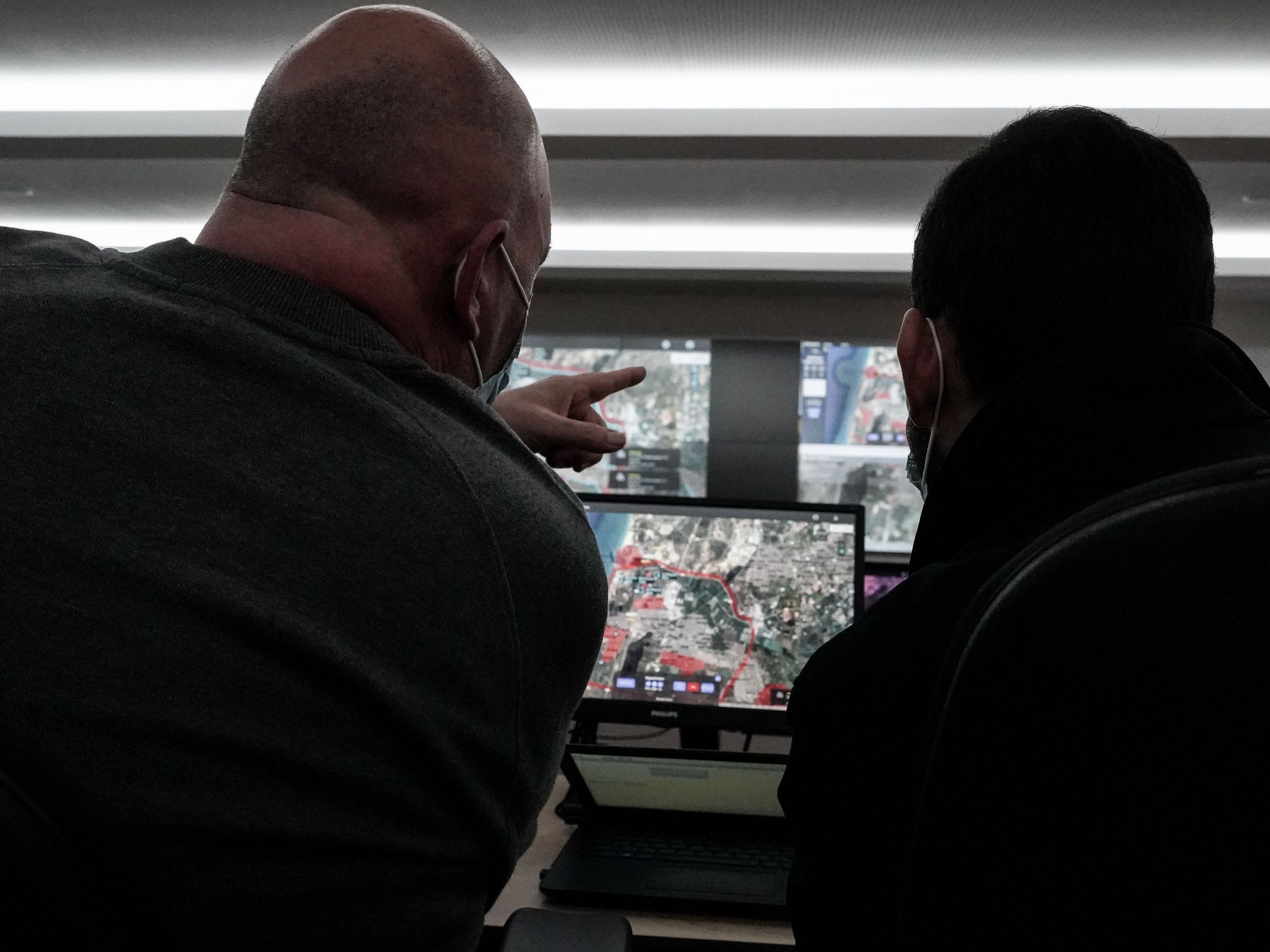 Two men look at various computer screens and point out details.