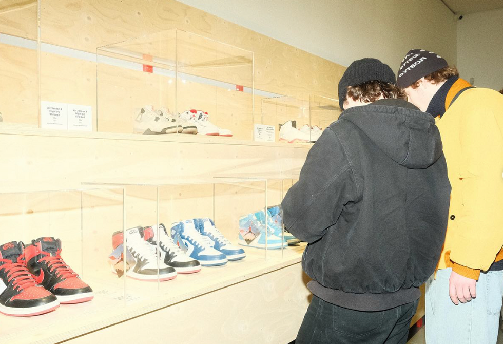 Two men stand and look at an exhibition of colorful sneakers.​
