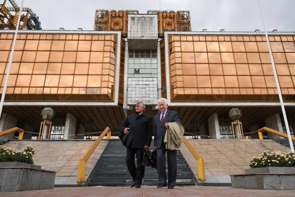 Two men stand outside the bronze facade of Russian Academy of Sciences