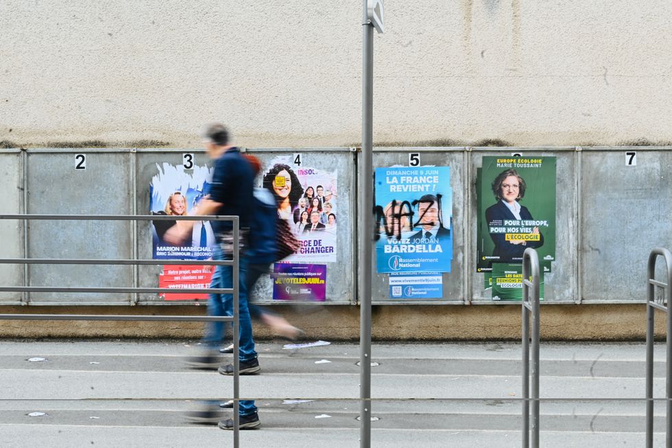 two people walking by a wall with 4 campaign posters for the European elections in the background