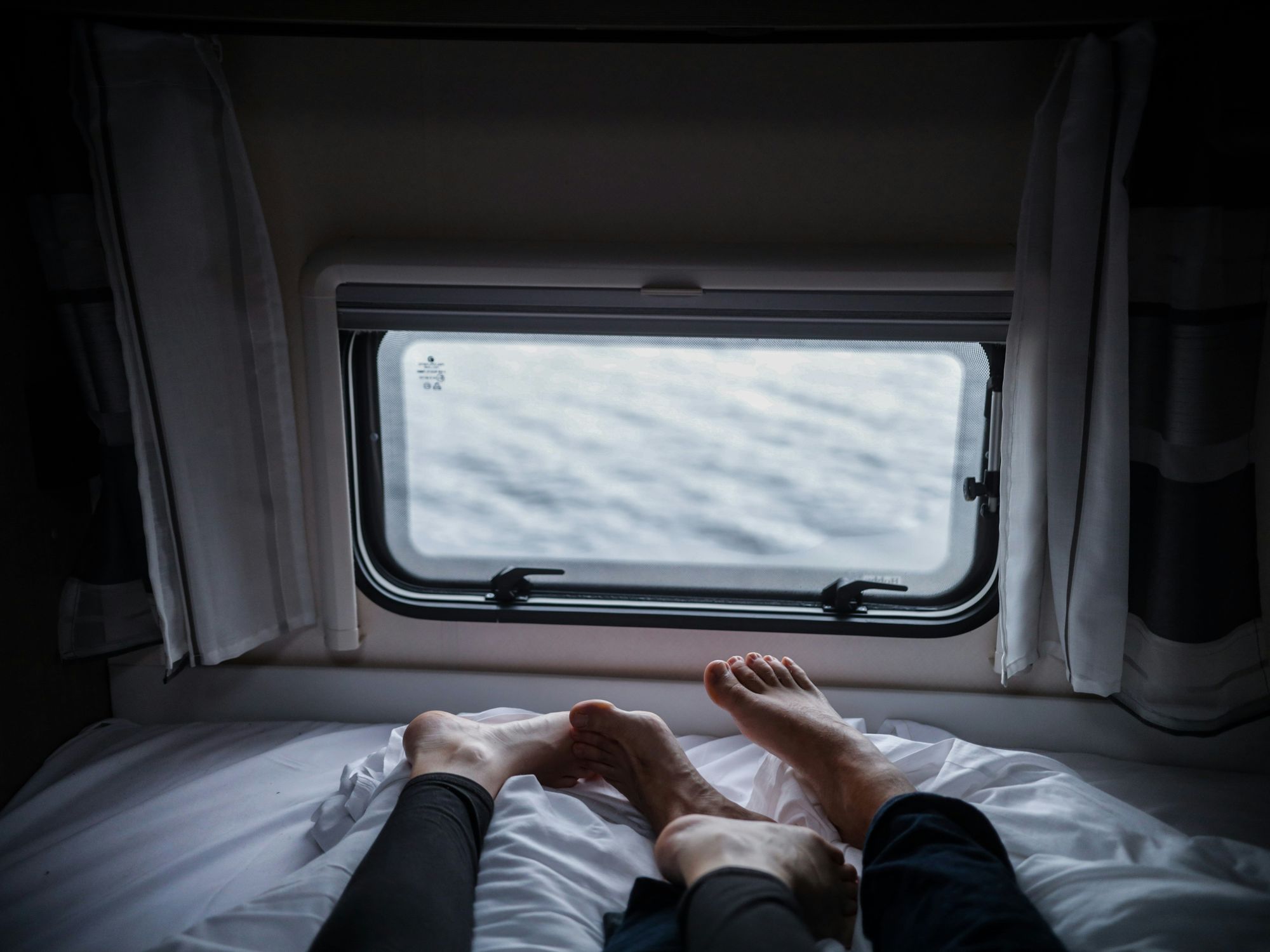 Two persons lying on a white bed.
