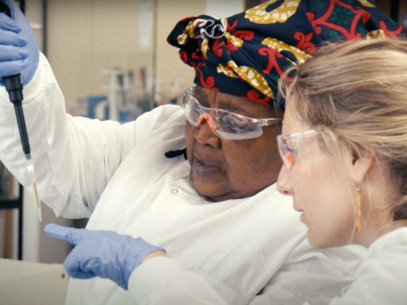 Two researchers work with a pipette dropper and wear safety glasses