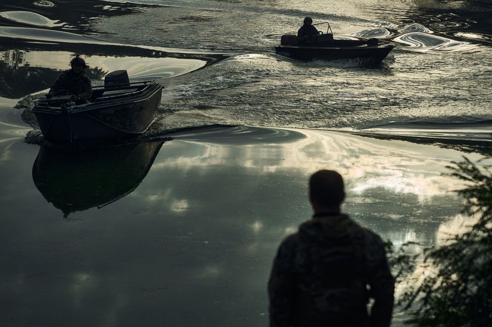 Two small boats, each with one soldier, cause a ripple in a river