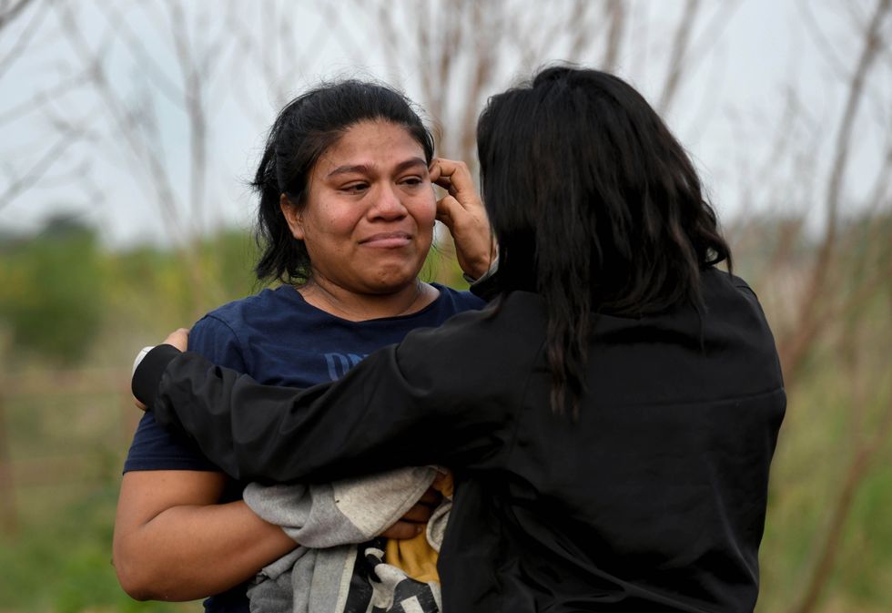 Two women comfort each other as they are processed along with other asylum-seeking migrants recently arriving illegally from Mexico.