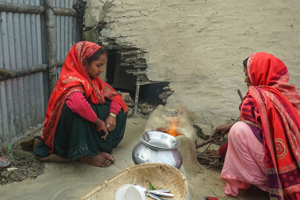 Two women cooking together outdoors.
