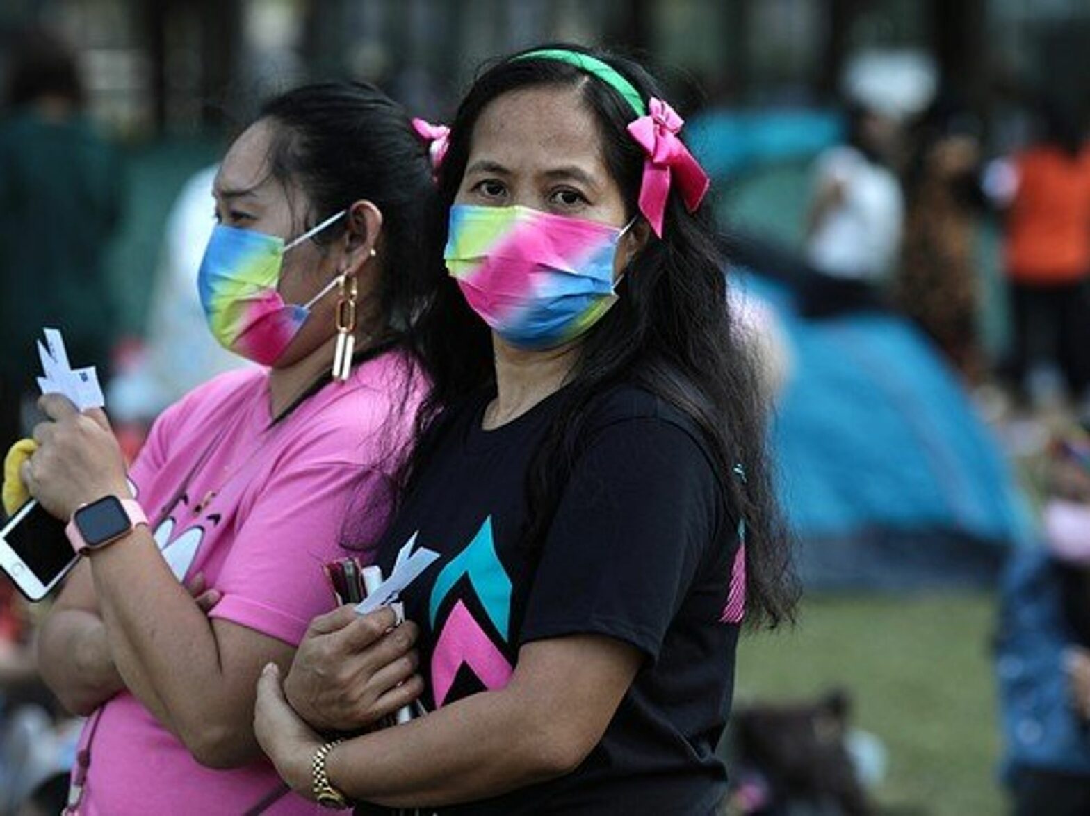 Two women standing with colorful masks on.