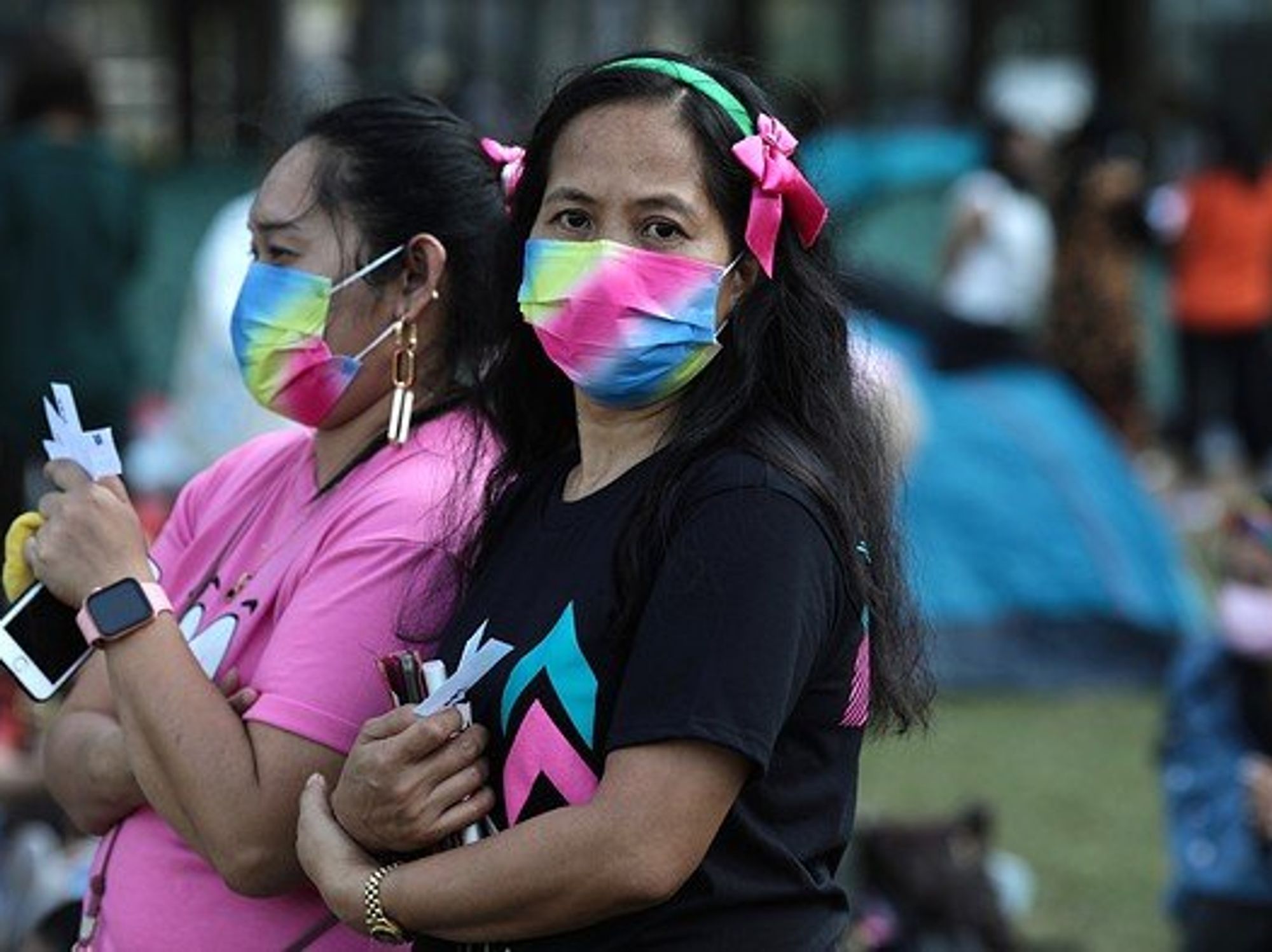 Two women standing with colorful masks on.