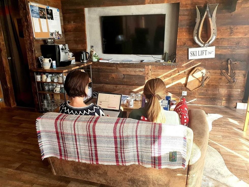 Two women working remotely from the couch of a nice cabin.