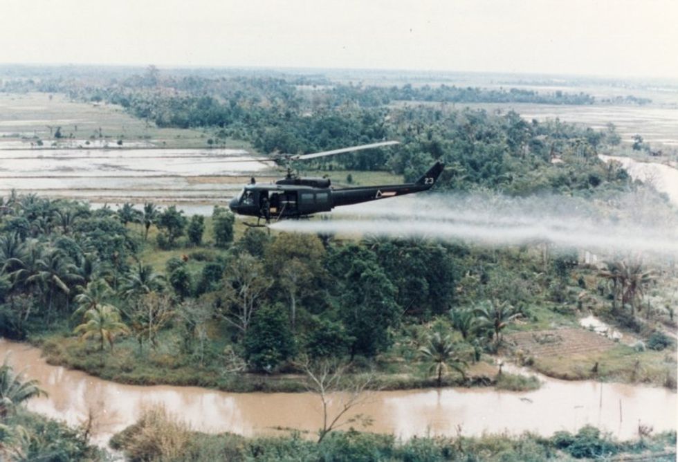 U.S. Army Huey helicopter spraying Agent Orange over agricultural land during the Vietnam War in 1963.