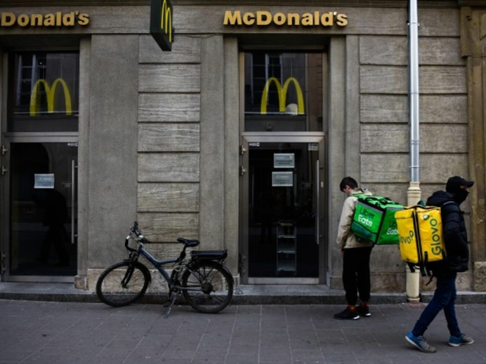 UberEats and Glovo workers wait for McDonald's meals to deliver to their costumers.