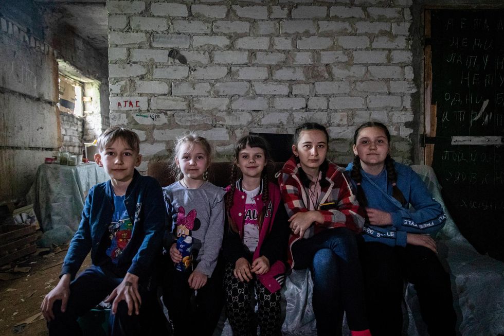 Ukraine: Children sit on a sofa in an underground shelter