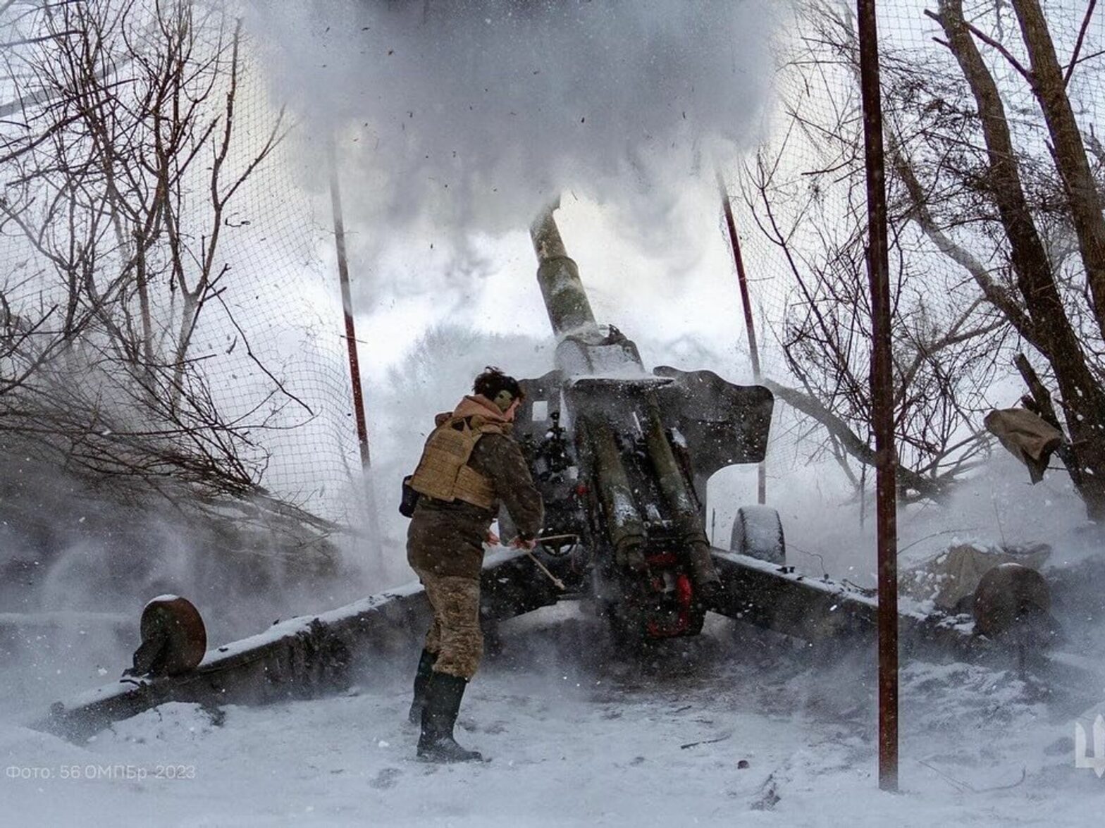 Ukraine soldier in winer firing a large canon with snow falling