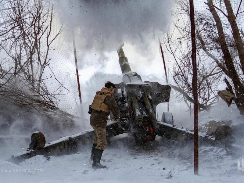 Ukraine soldier in winer firing a large canon with snow falling