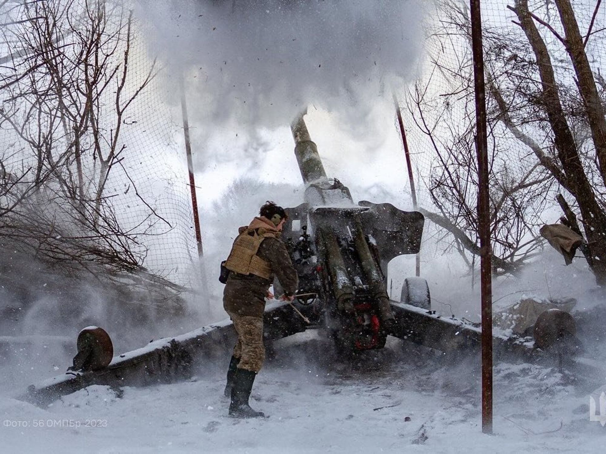 Ukraine soldier in winer firing a large canon with snow falling