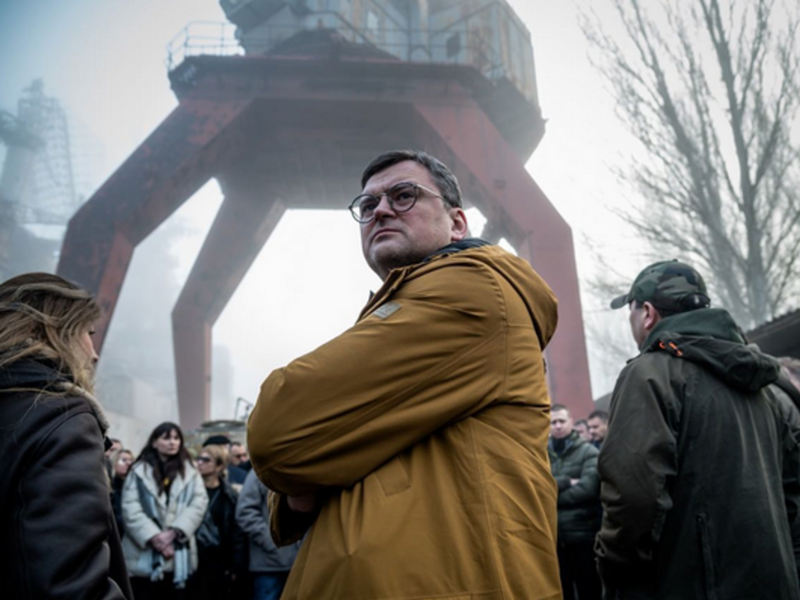 Ukrainian Foreign Minister Dmitry Kuleba stands in a crowd infront of towering machinery