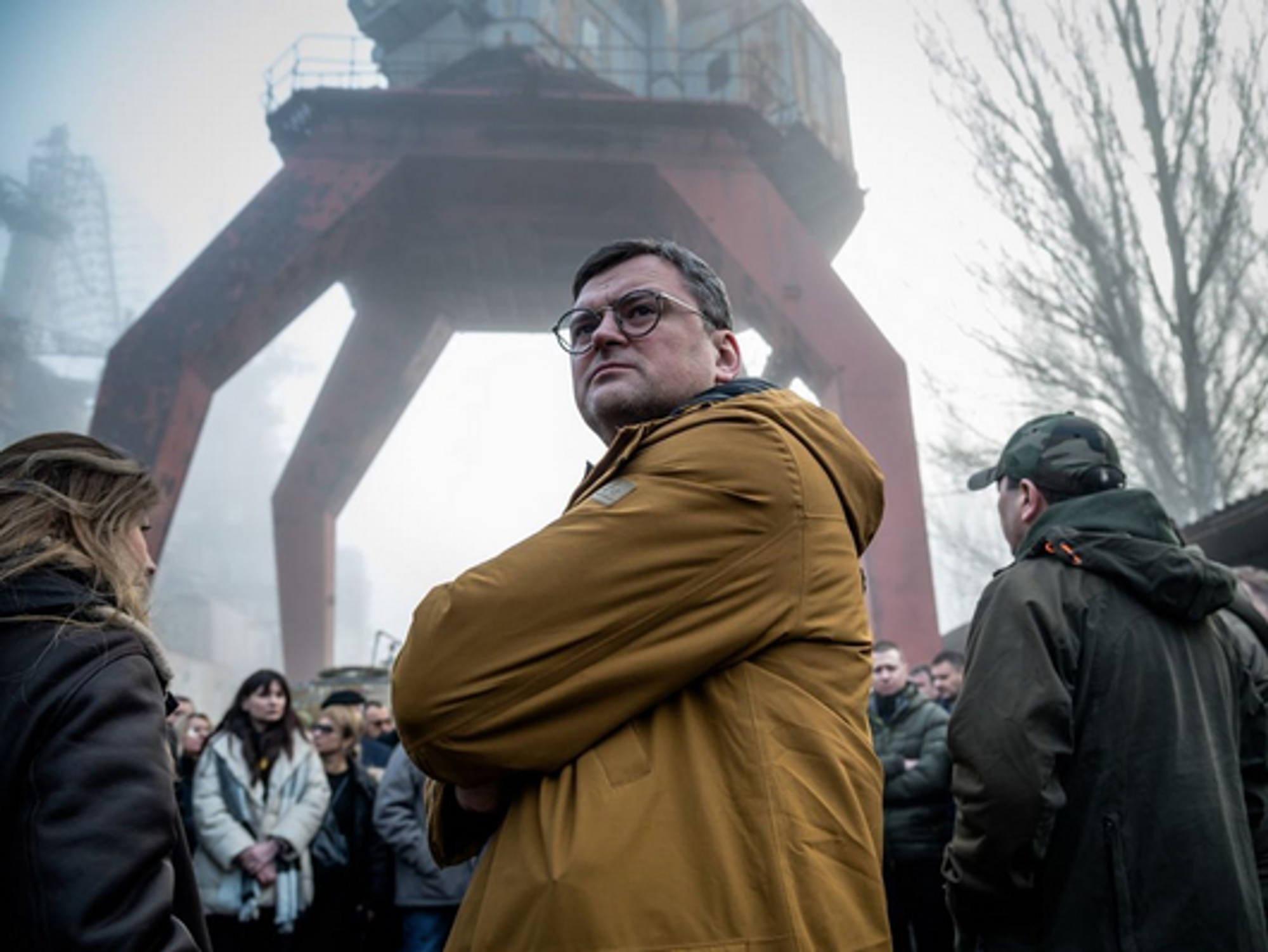 Ukrainian Foreign Minister Dmitry Kuleba stands in a crowd infront of towering machinery