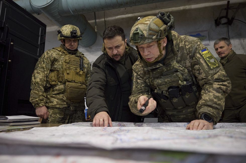 Ukrainian President Volodymyr Zelenskyy with two commanders looking over a map and pointing at it