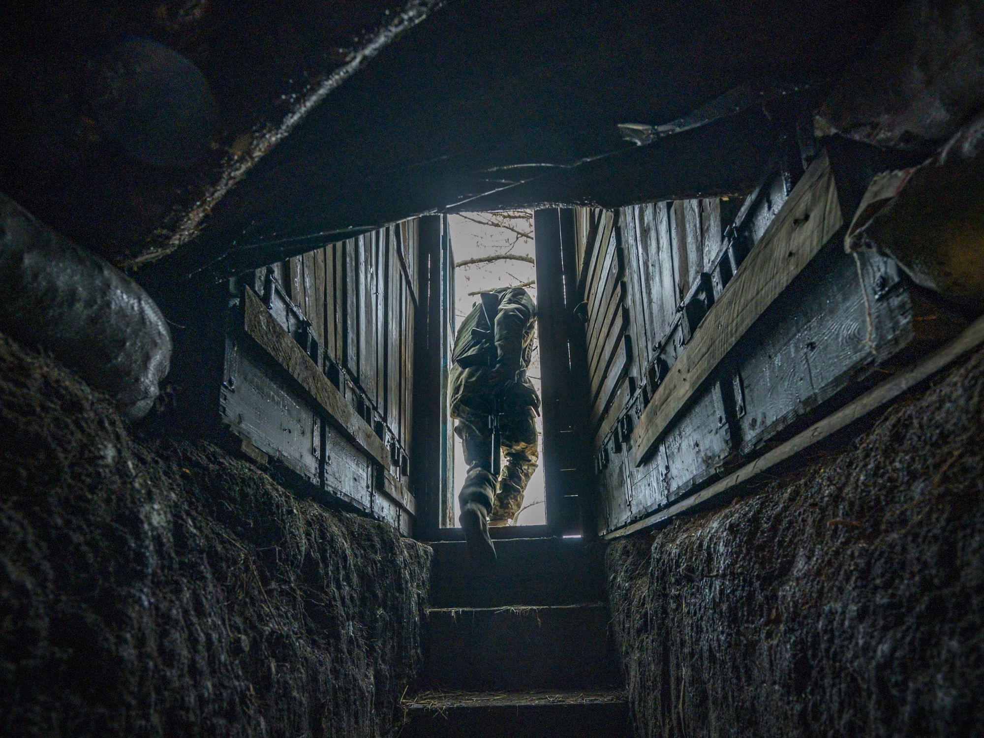 Ukrainian soldier climbing stairs from an underground shelter in Zaporizhia region, heading towards the entrance and the daylight