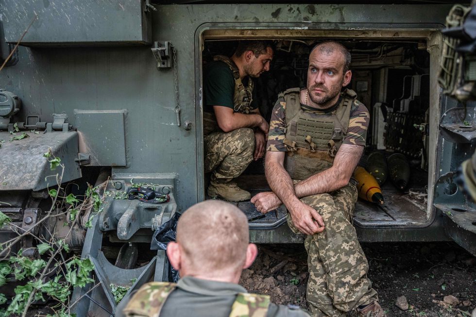 Ukrainian soldiers from the 33rd brigade crouch and sit inside an M109L artillery piece at a position near Kurakhove, in Donbas.