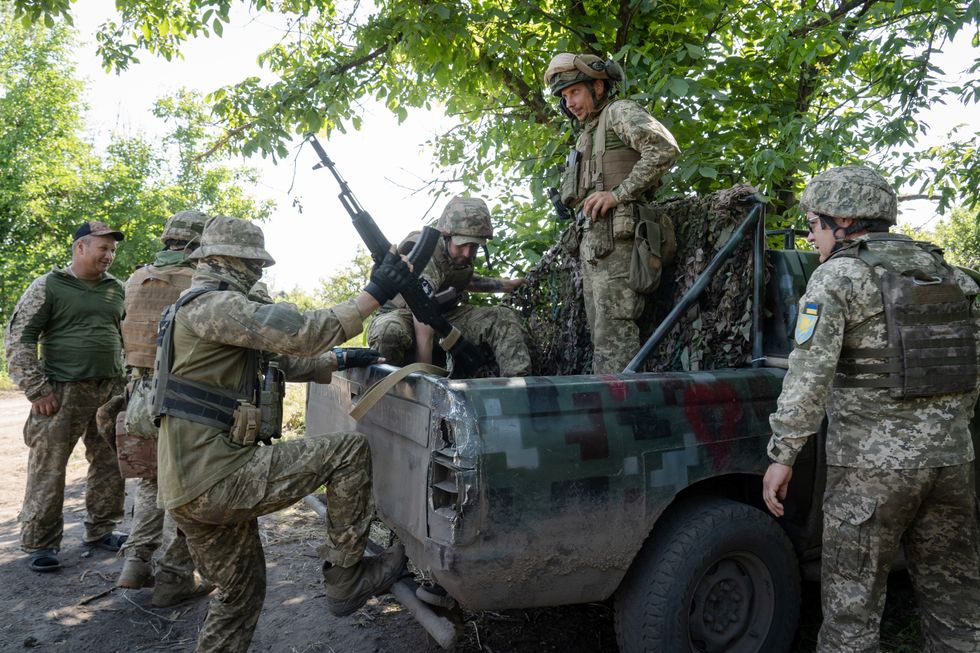 Ukrainian soldiers in camo climb into the back of a military truck