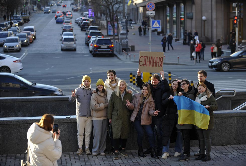 Ukrainians pose for a photograph with the Ukrainian flag and a placard that reads ''Unity'' in the center Kyiv, amid threats of Russian invasion.
