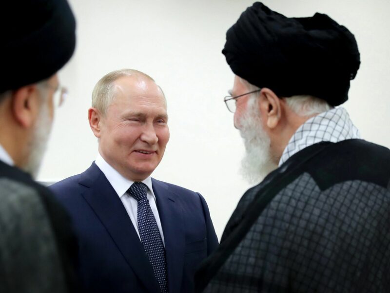 Vladimir Putin and Ali Khamenei greet each other in a nondescript room