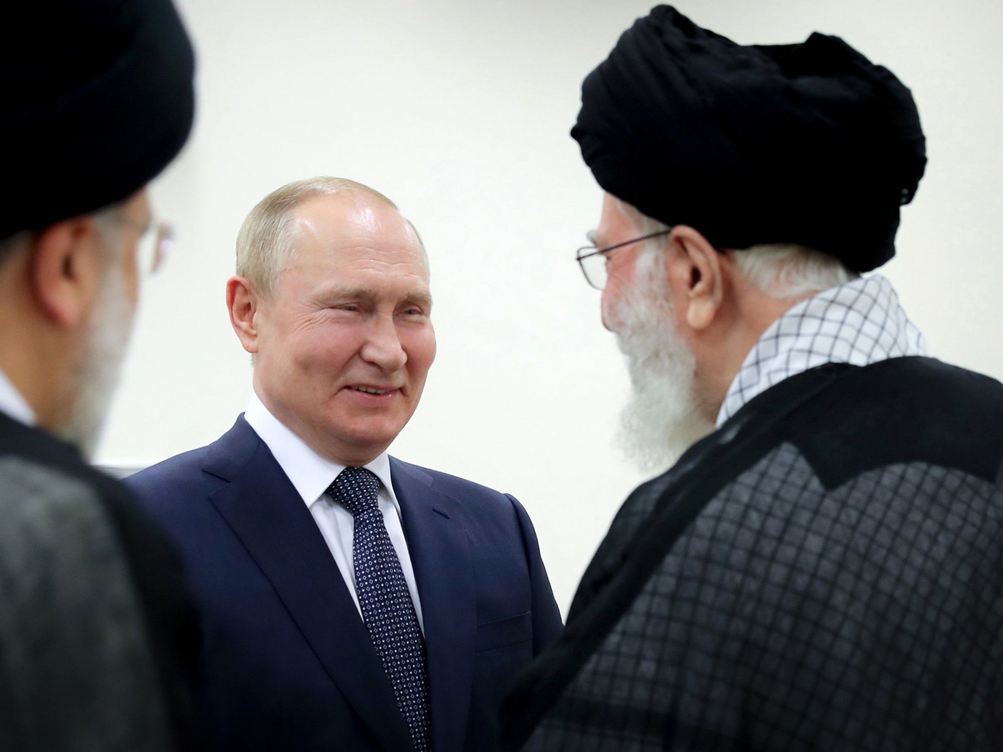 Vladimir Putin and Ali Khamenei greet each other in a nondescript room