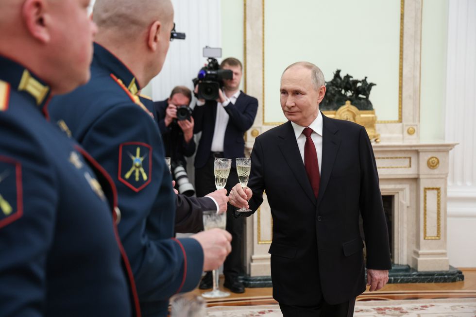 Vladimir Putin clinks glasses with servicemen after a ceremony to present Gold Star medals of Heroes of Russia to participants in the special military operation in Moscow, Russia, on February 23, 2025.