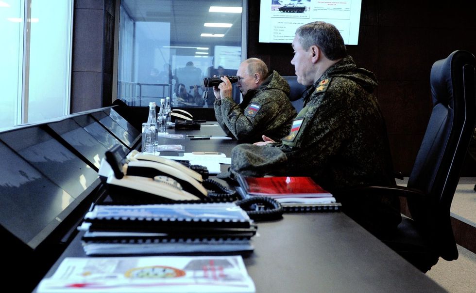 Vladimir Putin in a military outfit holds binoculars to observe the main stage of the Vostok-2022 strategic command post exercise at the Sergeyevsky range in the Primorye Territory.
