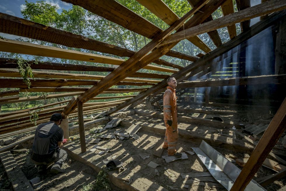 Volunteers work to rebuild a roof damaged by a Russian rocket launch.