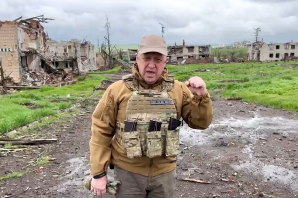 Wagner founder Prigozhin in military gear in front of destroyed buildings