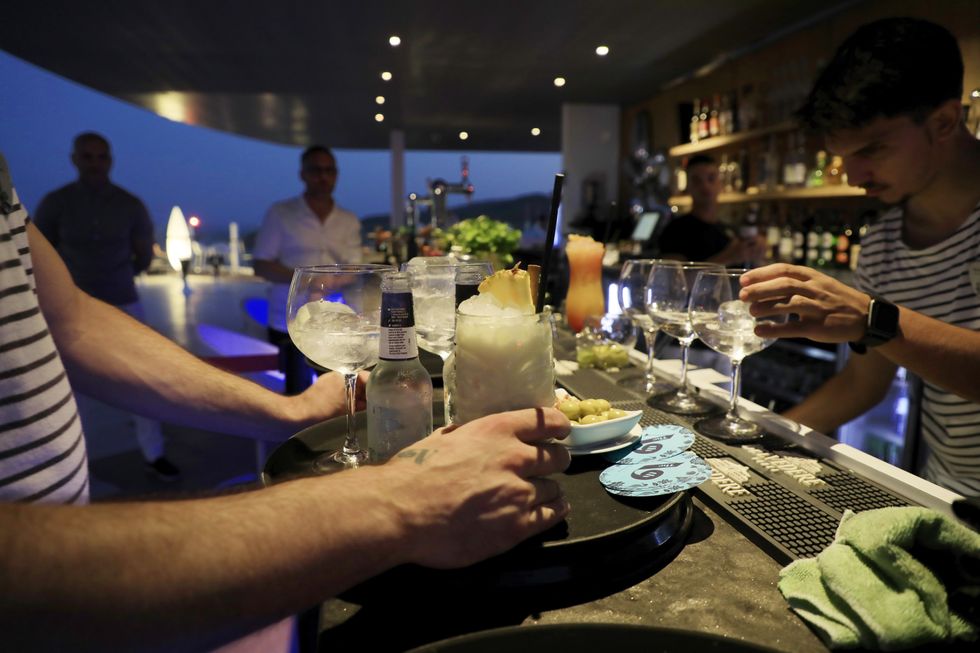 Waiters in striped t-shirts prepare drinks at a rooftop bar