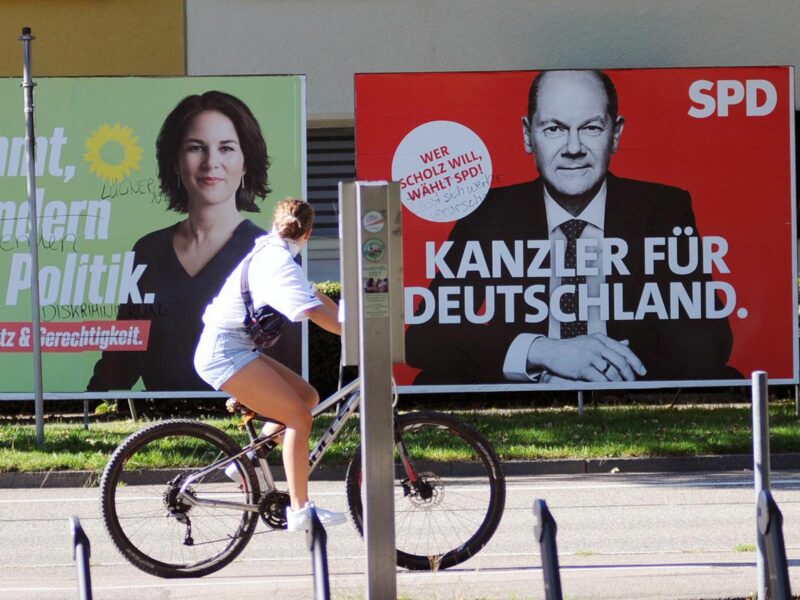 Woman cycling past election posters of Green and SPD candidates