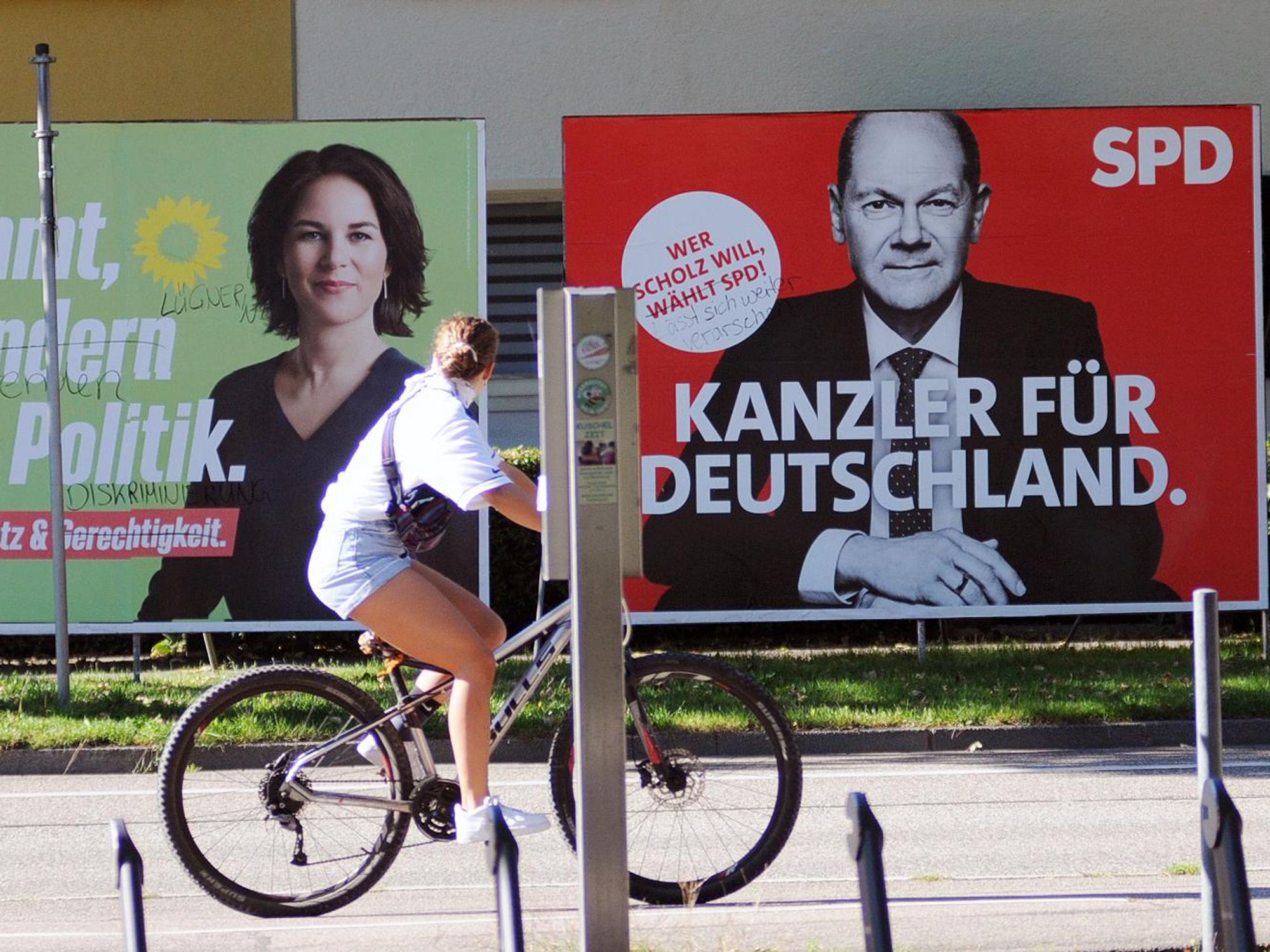 Woman cycling past election posters of Green and SPD candidates