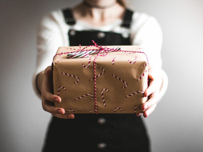 Woman in overalls holding a gift wrapper present to the audience