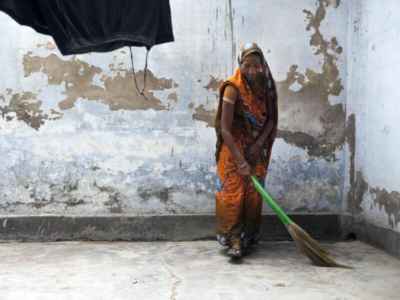 Woman sweeping her house in India.​