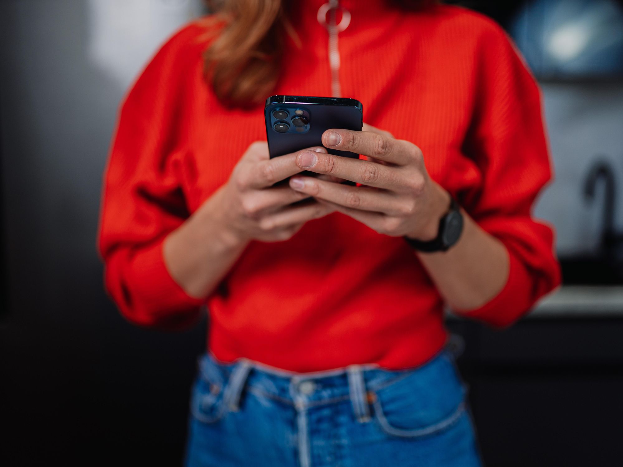 Woman with a bright red shirt holding an Iphone