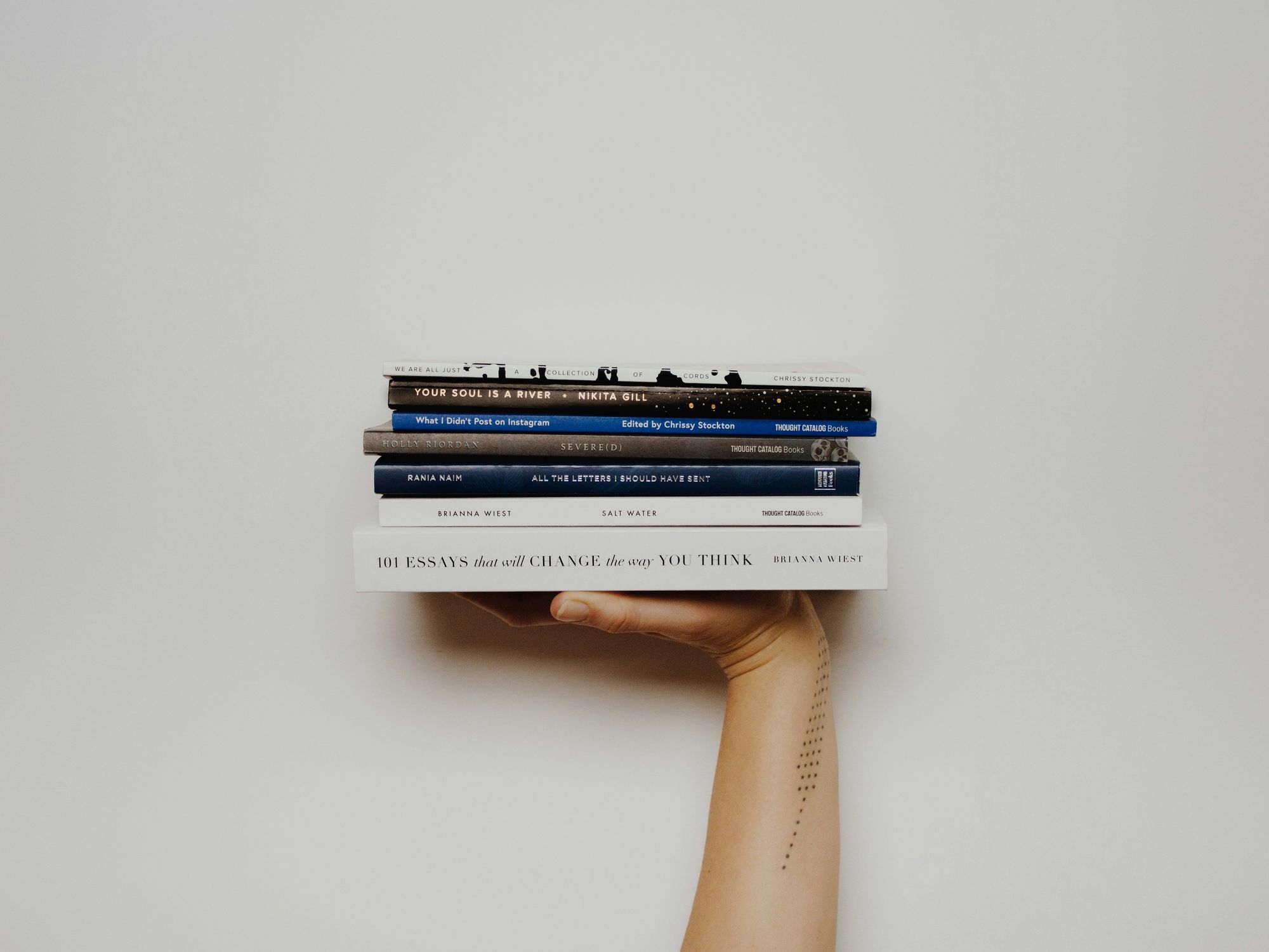 Woman with tattoo holding multiple small books.