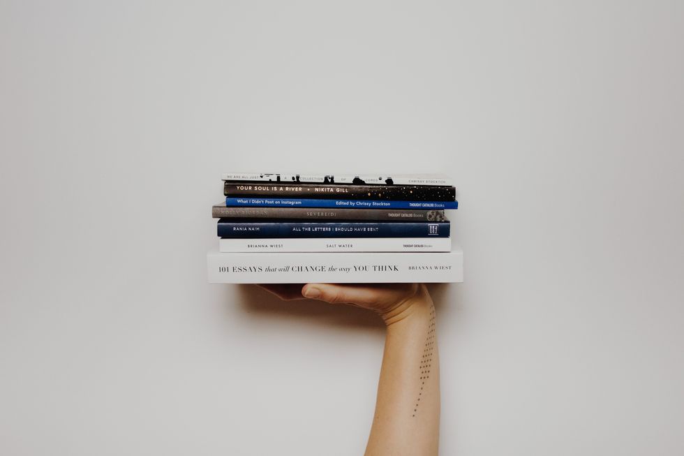 Woman with tattoos holding books.​