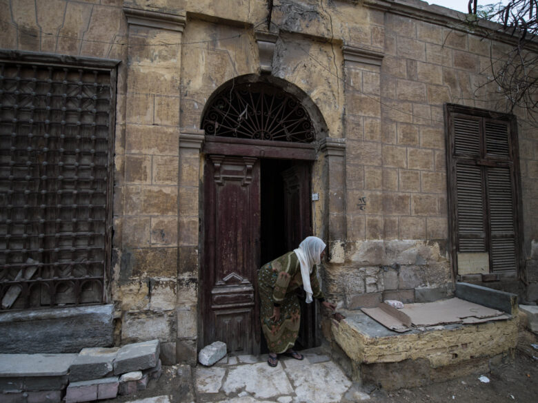 Women in Hijab bent over in front of a brick house