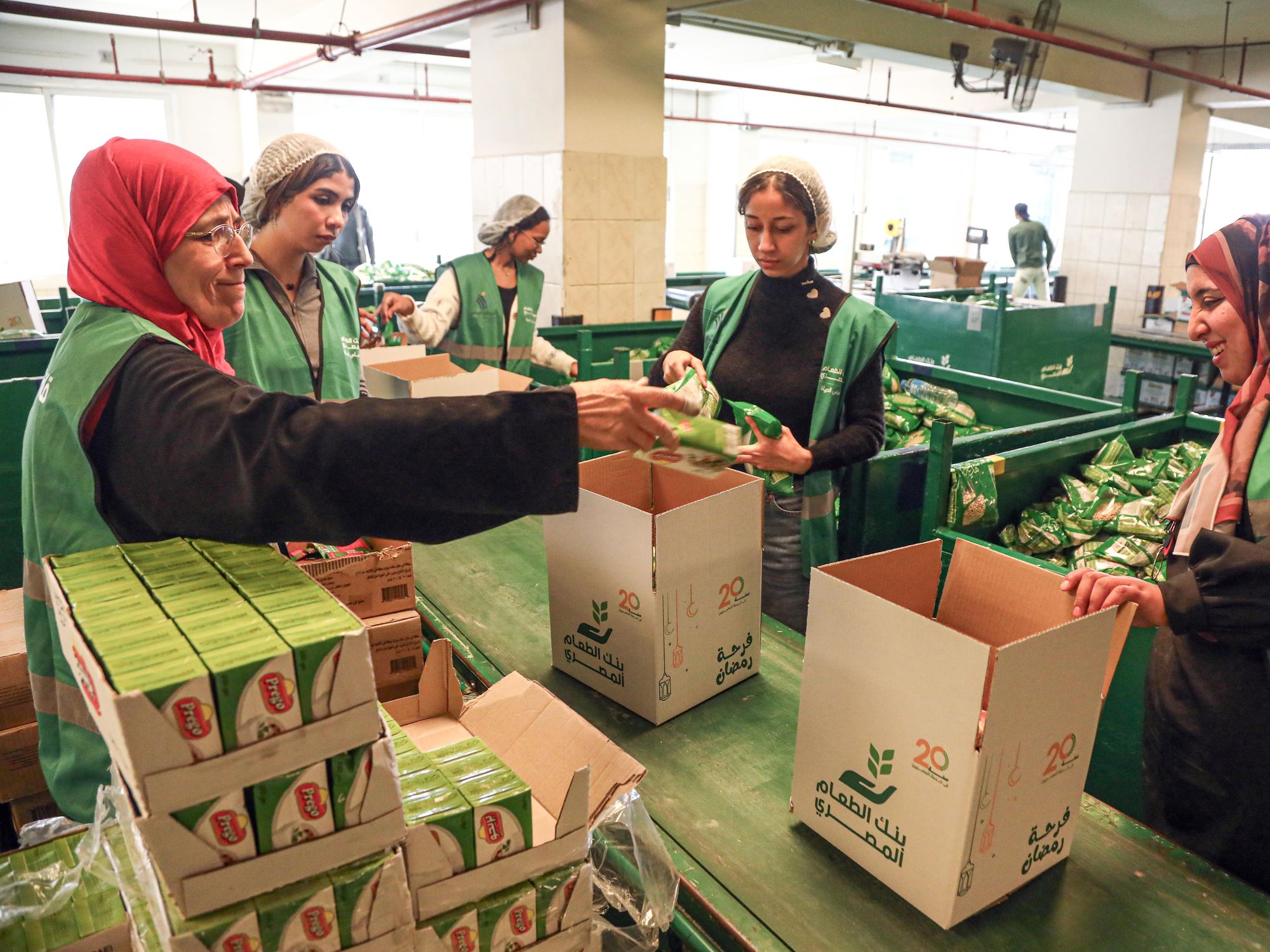 Workers and volunteers work to prepare free food boxes at the Egyptian Food Bank in Cairo, Egypt.​
