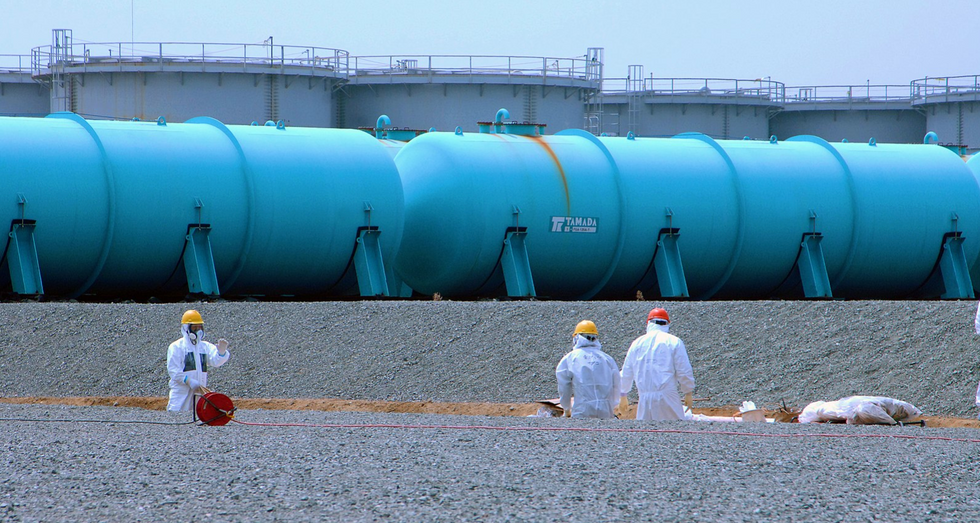 Workers at TEPCO's Fukushima Daiichi Nuclear Power Station work among underground water storage pools on 17 April 2013. Two types of above-ground storage tanks rise in the background.