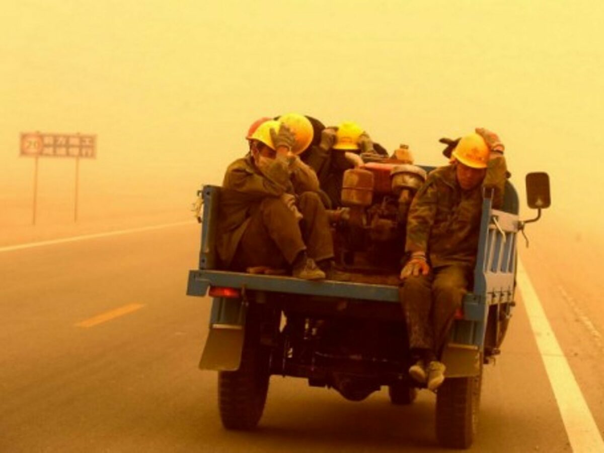 Workers facing a sandstorm Wednesday in southwestern China's Gansu province