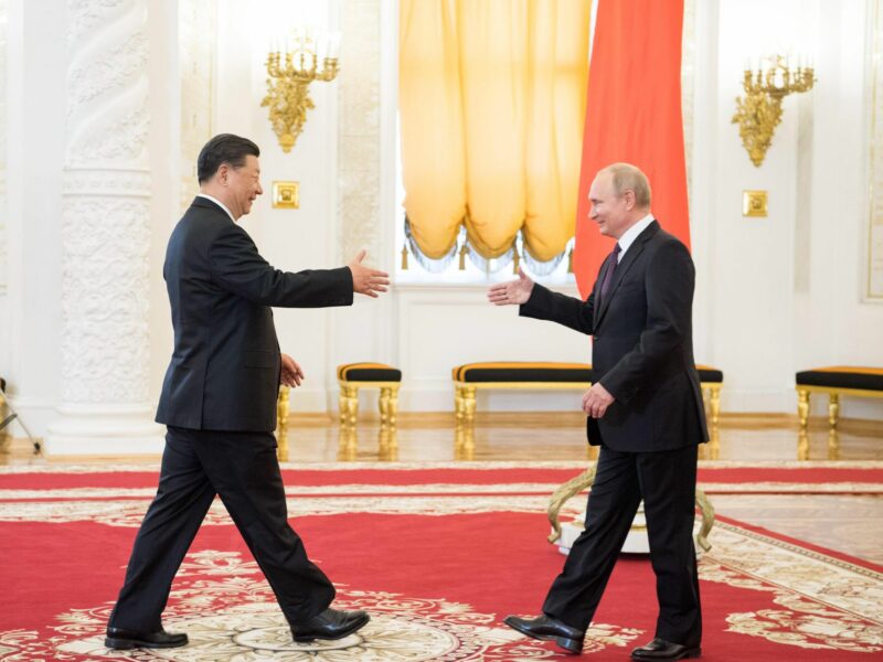 Xi Jinping and Vladimir Putin walking towards each other to shake hands